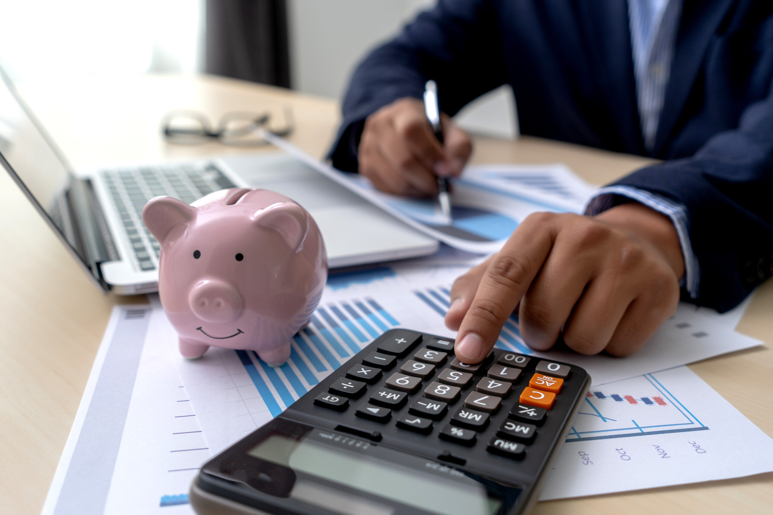 Homem fazendo cálculo na calculadora, com um porquinho de dinheiro ao lado