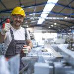 Homem em industria fazendo sinal de positivo
